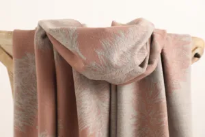 Double-sided cashmere scarf detail shot featuring elegant feather pattern and soft warm texture.