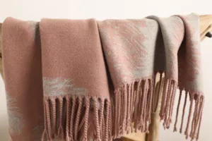 Detail shot of pink grey reversible cashmere winter scarf with feather pattern and tassels.