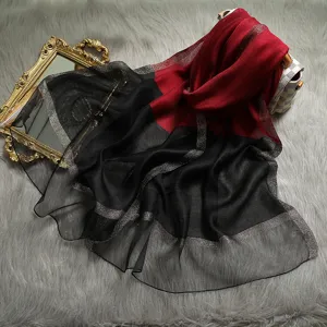 Plano detalle de la elegante bufanda de seda y lana roja y negra con rayas metalizadas.