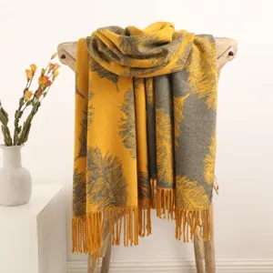 Detailed view of a cozy yellow and grey cashmere scarf with feather pattern and chic tassels.
