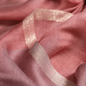 Detalle en primer plano de la bufanda rosa de mujer en seda y lana con borde brillante.