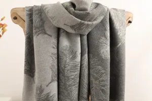 Detailed close-up of the grey cashmere scarf featuring elegant feather print and soft texture.