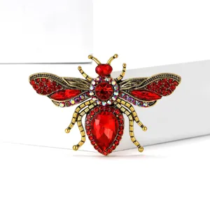 Detailed close-up shot of the rhinestone bee brooch, showing sparkling red crystals and metal.