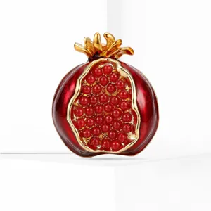 Detalle de broche granada exquisito, esmalte rojo y acabado dorado con cuentas.