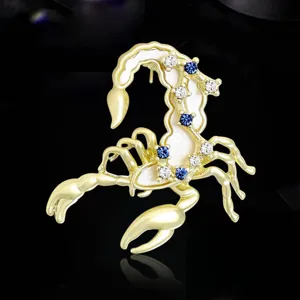 Vista dettagliata della spilla scorpione color oro con cristalli blu e bianchi per abiti.