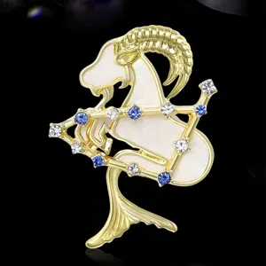 Spilla segno zodiacale Capricorno dorata con smalto bianco e cristalli scintillanti eleganti.