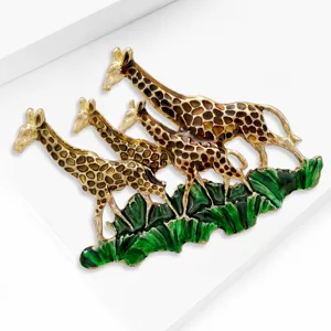 Détail de la broche girafe en émail montrant une finition métallique texturée et de l'herbe verte.