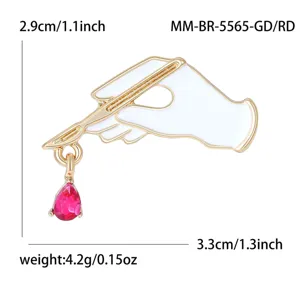 Detailed view of the medical scalpel and hand enamel brooch with red crystal pendant.
