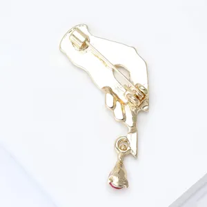 Close-up back detail of the gold alloy brooch showing the secure pin clasp and delicate drop charm.