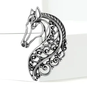 Close-up detail of vintage silver-tone hollow horse brooch with intricate filigree patterns.