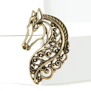 Close-up detail of vintage hollow bronze horse brooch with ornate filigree metal design.