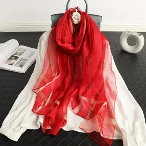 Detail view of a luxury red silk and wool blend scarf featuring elegant gold stripe patterns.