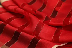 Silk wool blend scarf detail featuring elegant metallic gold stripes and rich red fabric texture.