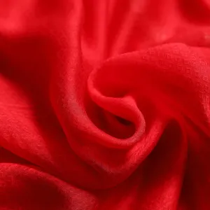 Detailed close-up of red silk fabric texture, showing smooth draping and subtle woven jacquard.
