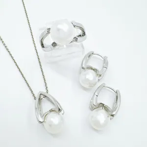 Detailed view of elegant pearl jewelry set featuring matching ring, pendant necklace, and earrings.