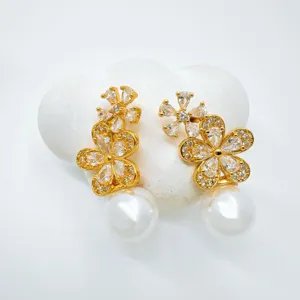 Detailed close-up of sparkling gold-plated flower cubic zirconia earrings with elegant pearl drops.