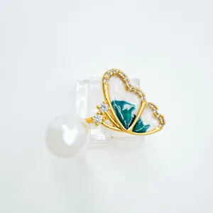 Exquisite butterfly pearl jewelry detail shot, gold plated copper with enamel drip oil and stones.