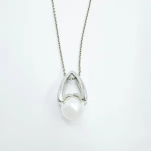 Elegant silver-tone metal and white pearl pendant necklace detail shot, niche fashion design.