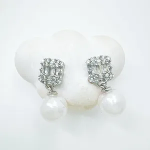 Detailed close-up of exquisite cubic zirconia pearl drop earrings displayed on a white cloud prop.