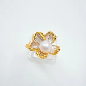 Detailed close-up of a elegant gold-rimmed flower pearl ring on transparent display.