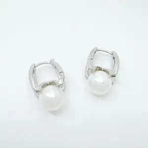 Close-up detail of silver metal hoop earrings with glossy white pearl charms, stylish design.