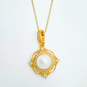 Close-up of luxury gold pearl pendant necklace featuring micro-paved crystals and clover motif.