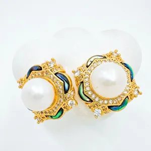 Detailed closeup of vintage gold pearl earrings with micro-inlaid zirconia and natural shell.
