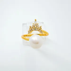Primer plano detallado del elegante anillo de perla con corona dorada, zirconias brillantes.