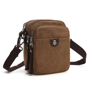 Close-up detail of brown canvas multi-compartment mini shoulder messenger bag strap.