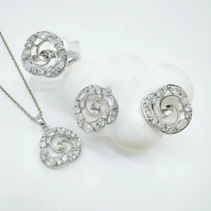 Close-up detail of silver rhinestone swirl jewelry set including necklace, earrings and ring.