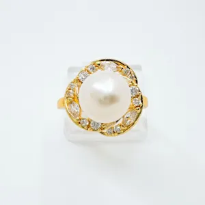 Close-up detail of luxury pearl ring with sparkling zircon stones and gold plated band.