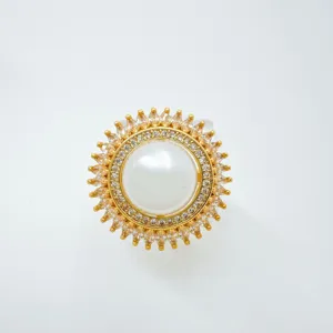 Detalle en primer plano del anillo dorado con perla grande y cristales brillantes elegantes.