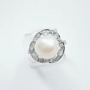Detail shot of an elegant pearl ring featuring a central white pearl and sparkling zirconia.