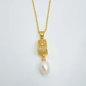 Close up detail of elegant gold plated pendant necklace featuring sparkling paved stones and natural pearl.