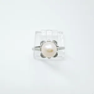 Primer plano detallado de un anillo de perlas con circonitas y una elegante montura metálica.