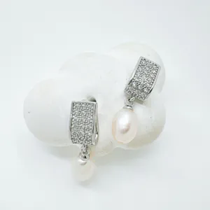 Close-up detail shot of exquisite pave stone rectangular earrings featuring elegant dangling pearls.