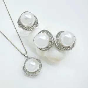 Detailed view of elegant geometric pearl jewelry set featuring pendant necklace, earrings and ring.