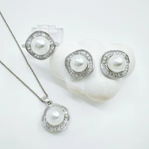 Close-up view of vintage pearl pendant necklace, earrings, and ring jewelry set with crystal halo.