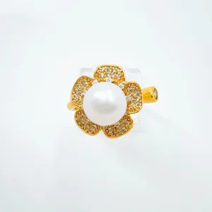 Nahaufnahme des eleganten Perlenrings mit vergoldeten Blütenblättern und funkelndem Zirkonia.