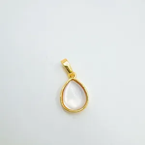 Primo piano di un ciondolo a goccia in madreperla e oro 18k, dettaglio di gioiello prezioso.
