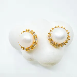 Scatto dettagliato di eleganti orecchini a perno con perle dorate e alone di zirconi lucidi.