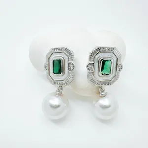 Close-up detail of vintage rectangular green gemstone pearl drop earrings with mother pearl.