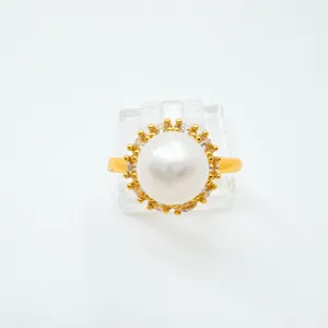 Dettaglio squisito anello perla oro con grande perla bianca e montatura di pietre lucide.