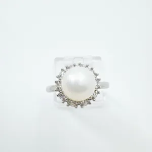Dettaglio di anello con perla elegante circondato da zirconi scintillanti e luminosi.
