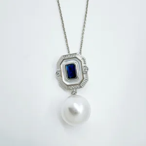 Close-up of vintage geometric pendant necklace featuring dark blue stone and white pearl.