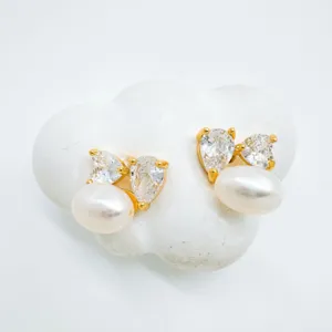 Close-up of pearl zirconia earrings, golden metal setting, elegant jewelry detail.