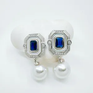 Close-up detail of vintage geometric rectangular blue crystal pearl earrings with white enamel frame.
