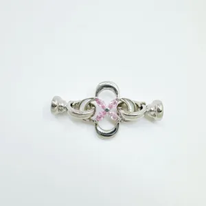 Gros plan detaille du fermoir de bijou argente avec design de fleur en zircone rose.