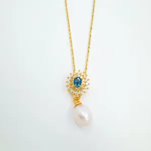 Vista detallada del collar con colgante de perla y zafiro, joyería dorada elegante.