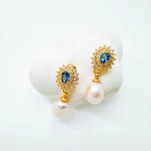 Detalle en primer plano de pendientes colgantes de perla y cristal azul vintage.